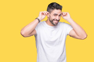 Yüksek sesle müzik gürültü rahatsız ifade parmaklarıyla kulaklarıyla kapsayan izole arka plan üzerinde rahat beyaz t-shirt giyen genç adam. Sağır kavramı.