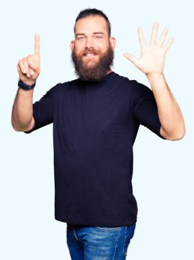 Gösterilen ve parmakları ile işaret rahat t-shirt giyen genç sarışın adam kendinden emin ve mutlu gülümseyerek süre 6 numara.
