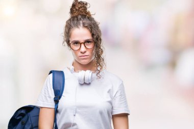 Sırt çantası ve kulaklık üzerinde giyen genç esmer öğrenci kız arka yüzünde ciddi bir ifade ile izole. Basit ve doğal kameraya bakıyor.