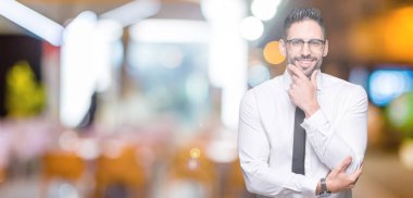 Emin çapraz kollar ve çeneme kaldırdı el ile gülümseme ile kameraya bakarak izole arka plan üzerinde gözlük takan genç yakışıklı iş adamı. Pozitif düşünce.