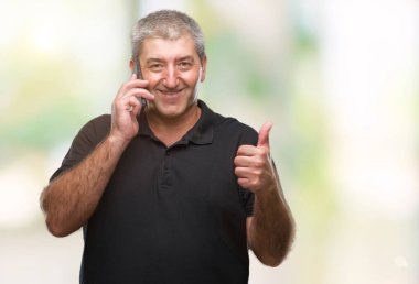 Üst düzey yakışıklı konuşmak Smartphone mutlu izole arka plan üzerinde ok işareti, başparmak ile parmak, mükemmel işareti yapıyor kocaman bir gülümseme ile