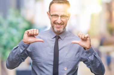Yüzünde gülümseme ile kendinden emin görünüyorsun, kendini gururlu ve mutlu parmakları ile işaret izole arka plan üzerinde gözlük takan orta yaş ağarmış üst düzey iş adamı.