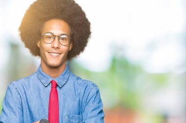 Gözlük ve kırmızı kravat mutlu yüz çapraz silah kameraya bakarak ile gülümseyen afro saçlı genç Afro-Amerikalı iş adamı. Olumlu bir kişi.
