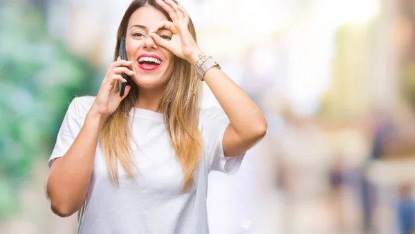 Young beautiful woman speaking calling using smartphone over isolated background with happy face smiling doing ok sign with hand on eye looking through fingers