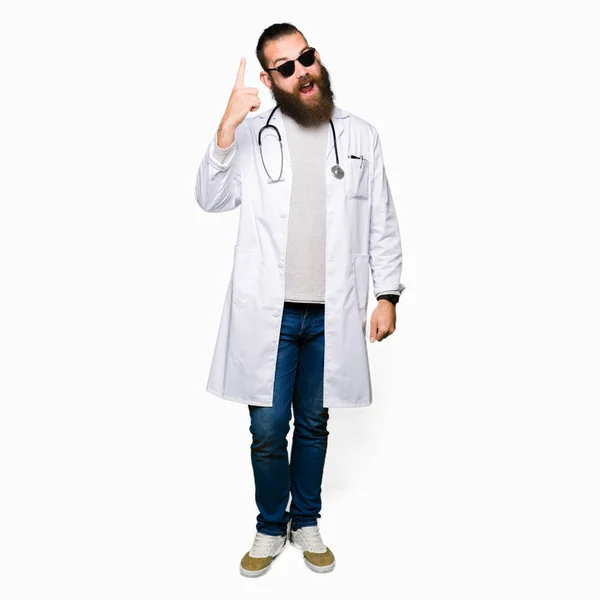 Młody Lekarz Blond Człowiek Brodą Noszenie Okularów Przeciwsłonecznych Wskazując Palcem — Zdjęcie stockowe