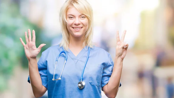 上医療ユニフォーム身に着けている美しい金髪女医女性分離を示す背景と指で上向き数は自信を持って 幸せな笑みを浮かべている間 — ストック写真