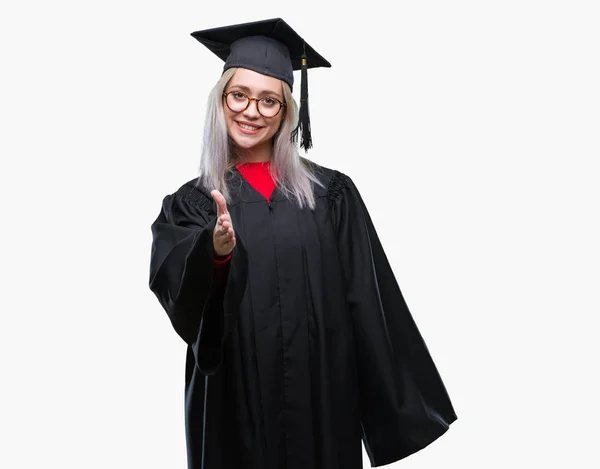 若いブロンドの女性の上の大学院の制服を着ては 挨拶と歓迎フレンドリーな提供ハンドシェイクを笑顔の背景を分離しました ビジネスの成功 — ストック写真