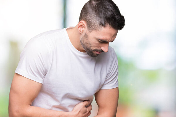 Young man wearing casual white t-shirt over isolated background with hand on stomach because nausea, painful disease feeling unwell. Ache concept.