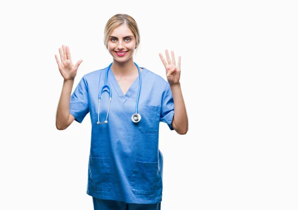 孤立した背景表示と指で上向きに若い美しい金髪の医者の外科医看護師女性ナンバー ナイン自信を持って 幸せな笑みを浮かべて — ストック写真