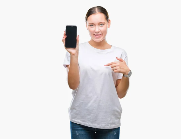年轻美丽的白人妇女显示智能手机屏幕在孤立的背景与惊讶的脸指向自己的手指 — 图库照片