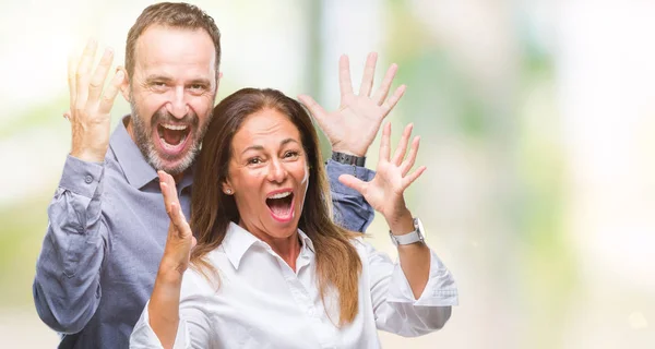 中年拉美裔商务情侣在孤立的背景下庆祝疯狂和惊讶的成功与手臂举起 睁开眼睛尖叫兴奋 赢家理念 — 图库照片