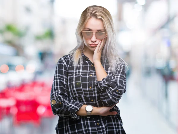 年轻的金发女子戴着太阳镜在孤立的背景下思考看累了 厌倦了与交叉手臂抑郁症问题 — 图库照片