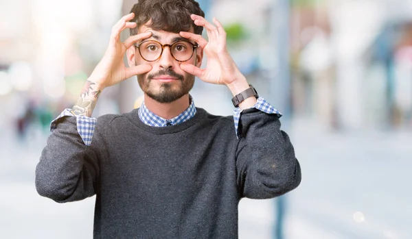 Genç yakışıklı parmaklarıyla, Uykulu ve sabah yorgunluk için yorgun gözlerini açmaya çalışırken izole arka plan üzerinde gözlük takan adam akıllı