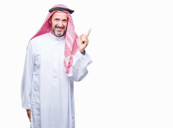 カメラを見て側に手と指で指して アラブ人をシニアの顔に大きな笑みを浮かべて隔離された背景にクーフィーヤを着て — ストック写真