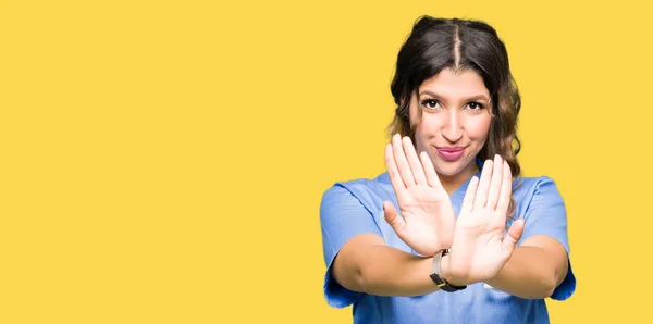 年轻的成年医生妇女穿着医疗制服的拒绝表情交叉手臂和手掌做负号 愤怒的脸 — 图库照片
