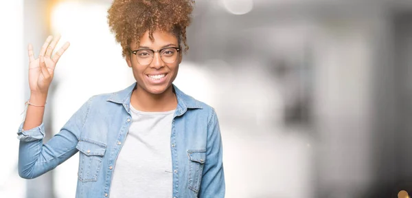 Beautiful young african american woman wearing glasses over isolated background showing and pointing up with fingers number four while smiling confident and happy.