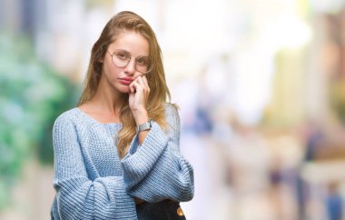 Kazak ve gözlük seyir yorgun ve bıkkın ile depresyon sorun Çapraz kollar ile izole arka plan düşünme üzerinde giyen genç güzel sarışın kadın.