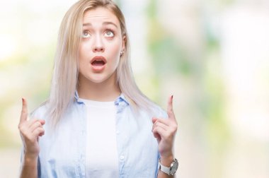 Sarışın genç kadın izole arka plan üzerinden hayran ve yukarıya bakıp parmakları ile işaret şaşırttı ve silah kaldırdı.