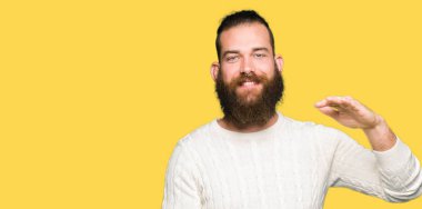 Kış kazak eller eller büyük gösterilen ve büyük boy işareti, ölçü birimi sembolü ile giyen genç hipster adam. Kameraya bakarak gülümsüyordu. Ölçüm kavramı.