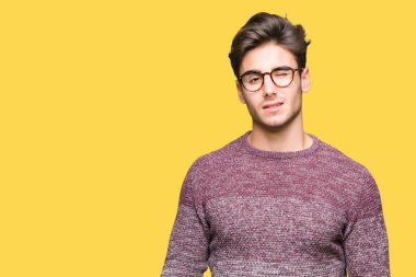 Seksi bir ifadeyle, neşeli ve mutlu yüzünü kameraya bakarak göz kırpıyor izole arka plan üzerinde gözlük takan genç yakışıklı adam.
