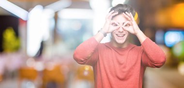 Yakışıklı delikanlı, dilini parmaklarının arasından baktığını yapışmasını dürbün gibi ok jest yapıyor izole arka plan üzerinde. Deli ifade.