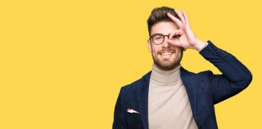 El gülümseyen, ok jest yapıyor genç yakışıklı iş adam gözlük göz parmakları ile mutlu yüz üzerinden seyir.