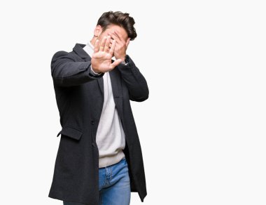 Zarif delikanlı üzerinde kış palto giyiyor izole elleriyle gözlerini kapsayan arka plan ve stop jest ile acı ve korku ifadesi. Utandım ve negatif kavramı.