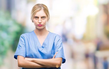 Genç güzel sarışın doktor cerrah hemşire kadın izole arka plan şüpheci ve çapraz kolları olan yüzündeki gergin, onaylamayan ifade yüzünden. Negatif kişi.