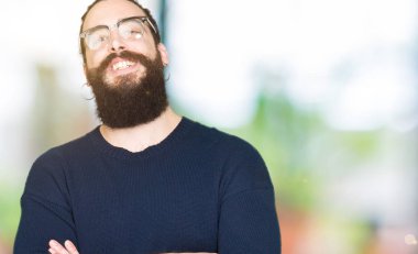 Uzun saç ve sakal ile gülümseyen bardakları mutlu yüz giyen genç hipster adamla silah kameraya bakarak geçti. Olumlu bir kişi.