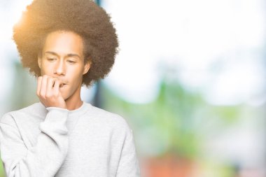 Afrikalı-Amerikalı genç afro saçlı sportif kazak stresli ve gergin elle çivi ısırma ağzına bakarak giyiyor. Anksiyete sorunu.