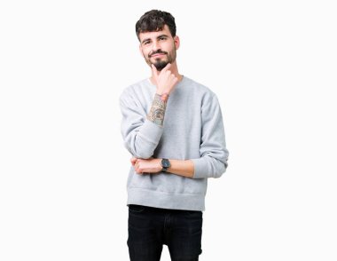 Emin çapraz kollar ve çeneme kaldırdı el ile gülümseme ile kameraya bakarak izole arka plan üzerinde kazak giyen genç yakışıklı adam. Pozitif düşünce.