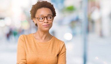 Genç güzel Afrikalı-Amerikalı kadın görünümlü yan ve dik dik bakma uzağa düşünce gülümseyen izole arka plan üzerinde gözlük.