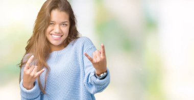 Deli ifade rock simge elle yapıyor ile bağırarak izole arka plan üzerinde mavi kış kazak giyen genç güzel esmer kadın. Müzik yıldızı. Ağır kavramı.