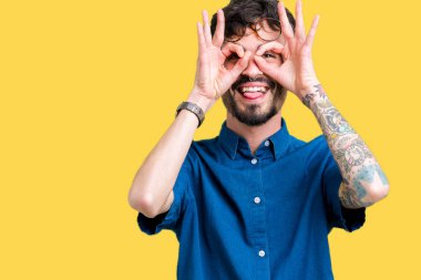 Dilini, parmaklarının arasından baktığını yapışmasını dürbün gibi ok jest yapıyor izole arka plan üzerinde gözlük takan yakışıklı delikanlı. Deli ifade.