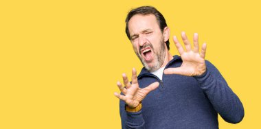 Şokta bağırarak korkuyor ve dehşet korku ifade dur hareketi el ile ile kazak giyen orta yaş yakışıklı adam. Panik kavramı.