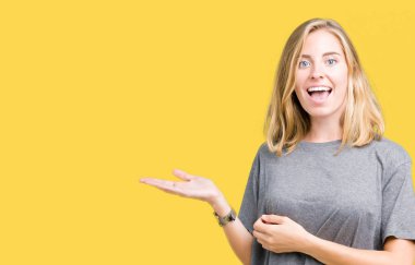 Güzel genç kadın üzerinde büyük boy rahat t-shirt giyen izole arka plan el ve reklam mutlu ve kendinden emin gülümseyen sunulması avuç, yanında işaret