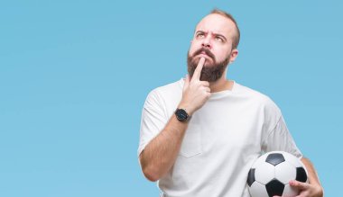İzole arka plan ciddi bir yüz düşünme hakkında soru, çok karışık bir fikir üzerinde futbol futbol topu tutan genç beyaz hipster adam