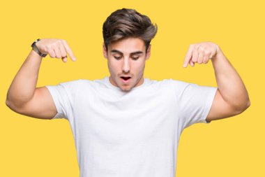 Beyaz t-shirt üzerinde izole giyen genç yakışıklı adam arka plan işaretleme aşağı reklam, sürpriz yüz ve açık ağız gösterilen parmakları ile