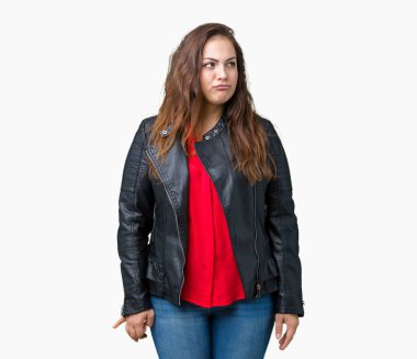 Artı boyutu genç kadın güzel üzerinde bir moda deri ceket giyiyor arka plan görünümlü yan ve dik dik bakma uzağa düşünce gülümseyen izole.