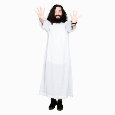 Gösterilen ve parmakları ile işaret İsa Mesih giyinen adam kendinden emin ve mutlu gülümseyerek ise dokuz numara.