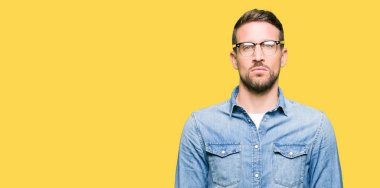 Yakışıklı adam gevşek ciddi ifade ile yüzünde gözlüklü. Basit ve doğal kameraya bakıyor.