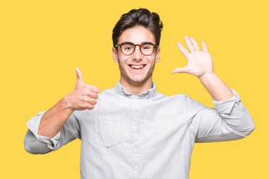 Gösterilen arka plan üzerinde gözlük takan genç yakışıklı adam izole ve parmakları ile işaret kendinden emin ve mutlu gülümseyerek süre 6 numara.