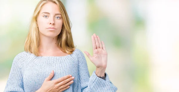 美丽的年轻女子穿着蓝色毛衣在孤立的背景发誓用手在胸部和开放的手掌 作出忠诚承诺誓言 — 图库照片