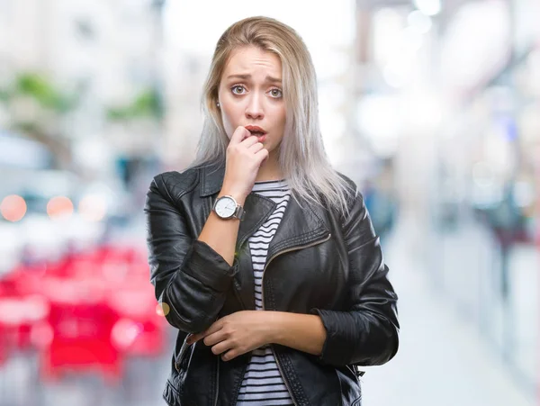 年轻的金发女子穿着时尚夹克在孤立的背景下看紧张和紧张与手在嘴咬指甲 焦虑问题 — 图库照片