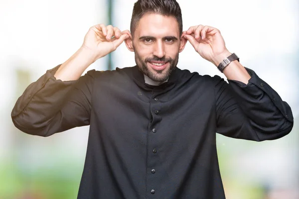 Jovem Padre Cristão Sobre Fundo Isolado Sorrindo Puxando Orelhas Com — Fotografia de Stock