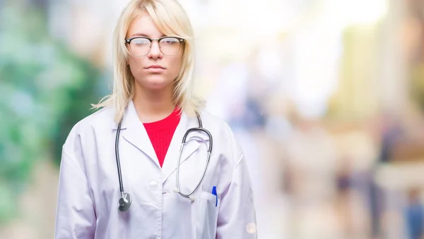 年轻美丽的金发医生妇女穿着医疗制服在孤立的背景下 面部表情严肃 简单而自然地看着相机 — 图库照片