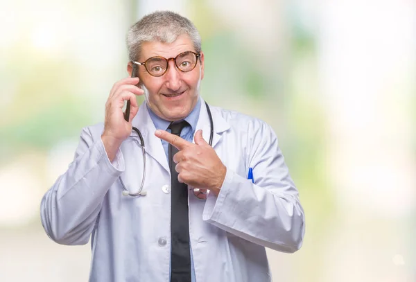 非常に幸せな手と指で指している孤立した背景の上 Smarpthone に話しているハンサムな先輩医師男性 — ストック写真