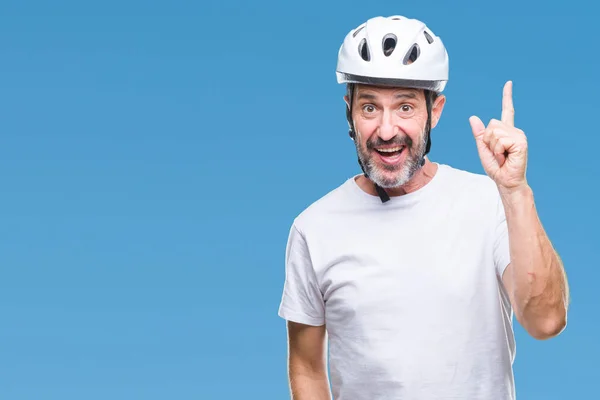 Middle age senior hoary cyclist man wearing bike safety helment isolated background pointing finger up with successful idea. Exited and happy. Number one.