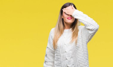 Genç güzel kadın gülümsüyor ve gözleri için sürpriz kapsayan yüz el ile gülüyor izole arka plan üzerinde rahat beyaz kazak. Kör kavramı.