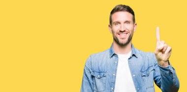 Yakışıklı adam mavi gözleri ve denim ceket gösterme ve kendinden emin ve mutlu gülümseyen bir parmak ile işaret eden oktan yukarı giyen sakal.